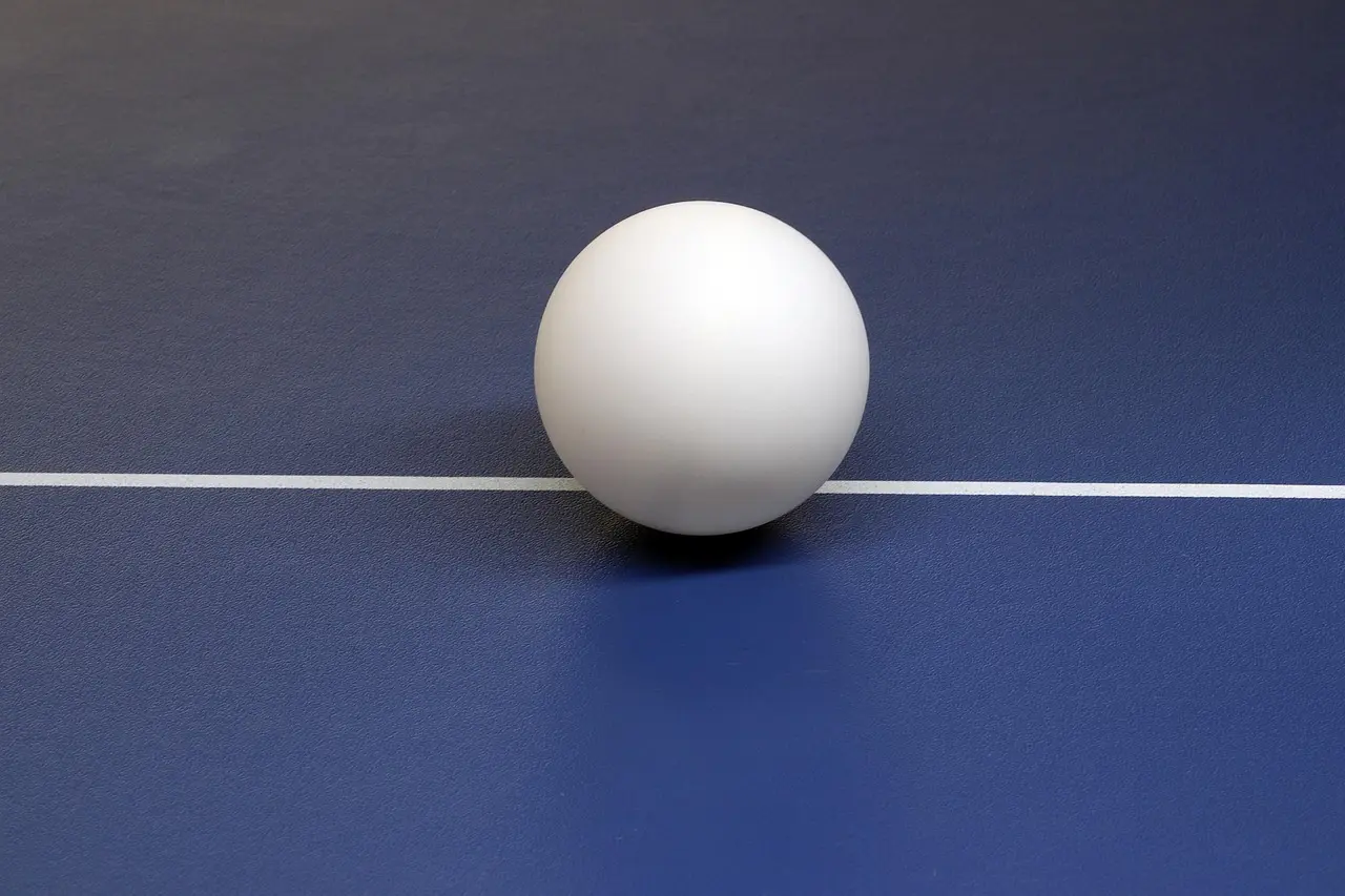 Bordtennisbold på blåt bordtennisbord med hvid midterlinje