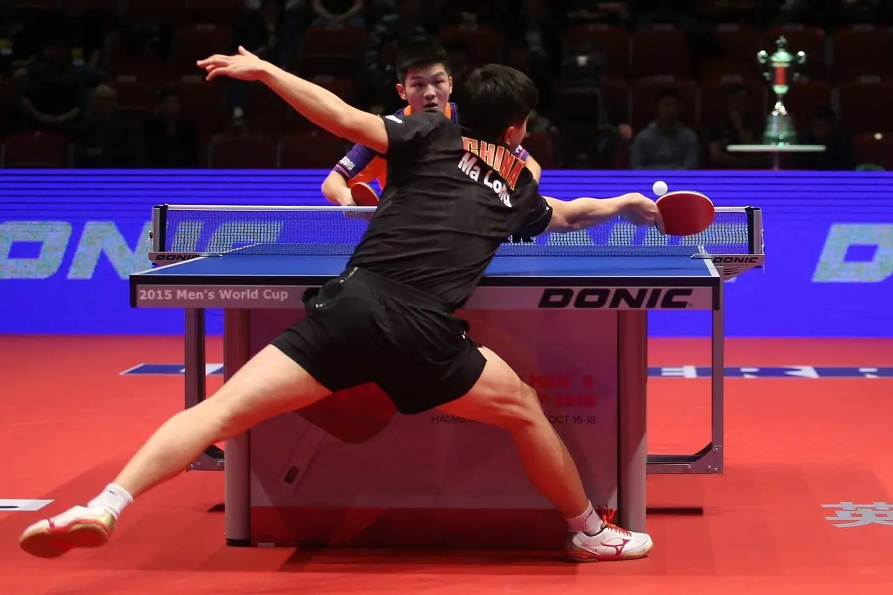 To bordtennisspillere i kamp ved et bordtennisbord